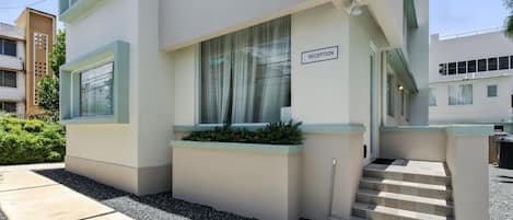 Un edificio moderno con recepción, escalones que conducen a la entrada y un pequeño jardín.
