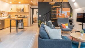Una cocina moderna con armarios de madera, microondas integrado y un comedor con sofá azul y una mesa de centro.