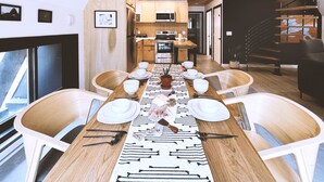Una cocina moderna con armarios de madera, electrodomésticos de acero inoxidable y una zona de comedor con una mesa grande para seis personas.