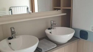 Et badeværelse med to hvide vaske, et spejl og en håndklædestang.