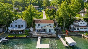 Una propietat al costat del mar amb un moll, una casa amb terrassa i un vaixell.