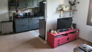 Un espai vital reduït amb zona de cuina, un moble de sobretaula rosa i una taula petita amb objectes decoratius.