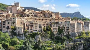 Un poble històric amb edificis de pedra, un terreny accidentat i un paisatge de muntanyes al fons.