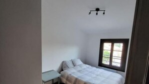 Un dormitori amb un llit, una taula petita i una finestra.
