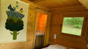 Ein Zimmer in einer Holzhütte mit einem Bett, einem Fenster und einer Tür zu einem Badezimmer.