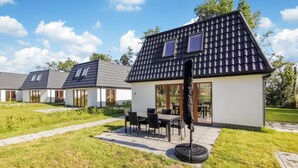 A modern house with a tiled roof, a patio with a table and chairs, and a number '17' on the wall. - Gorgeous home in Den Oever with WiFi (Den Oever)