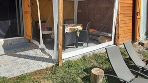 A covered patio area with a table and chairs, a wooden door, and a tiled floor. - Joli Pavillon Individuel et Privatif (Rigaud)