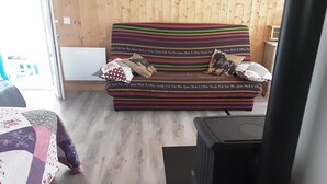 A room with a striped sofa, a quilted table, and a black heater. - Joli Pavillon Individuel et Privatif (Rigaud)