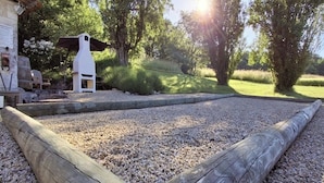 Un'area giardino con struttura in legno, terreno sterrato e alberi.