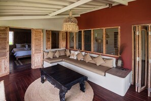 Una habitación con un banco de madera, un sofá y una cama con vistas.