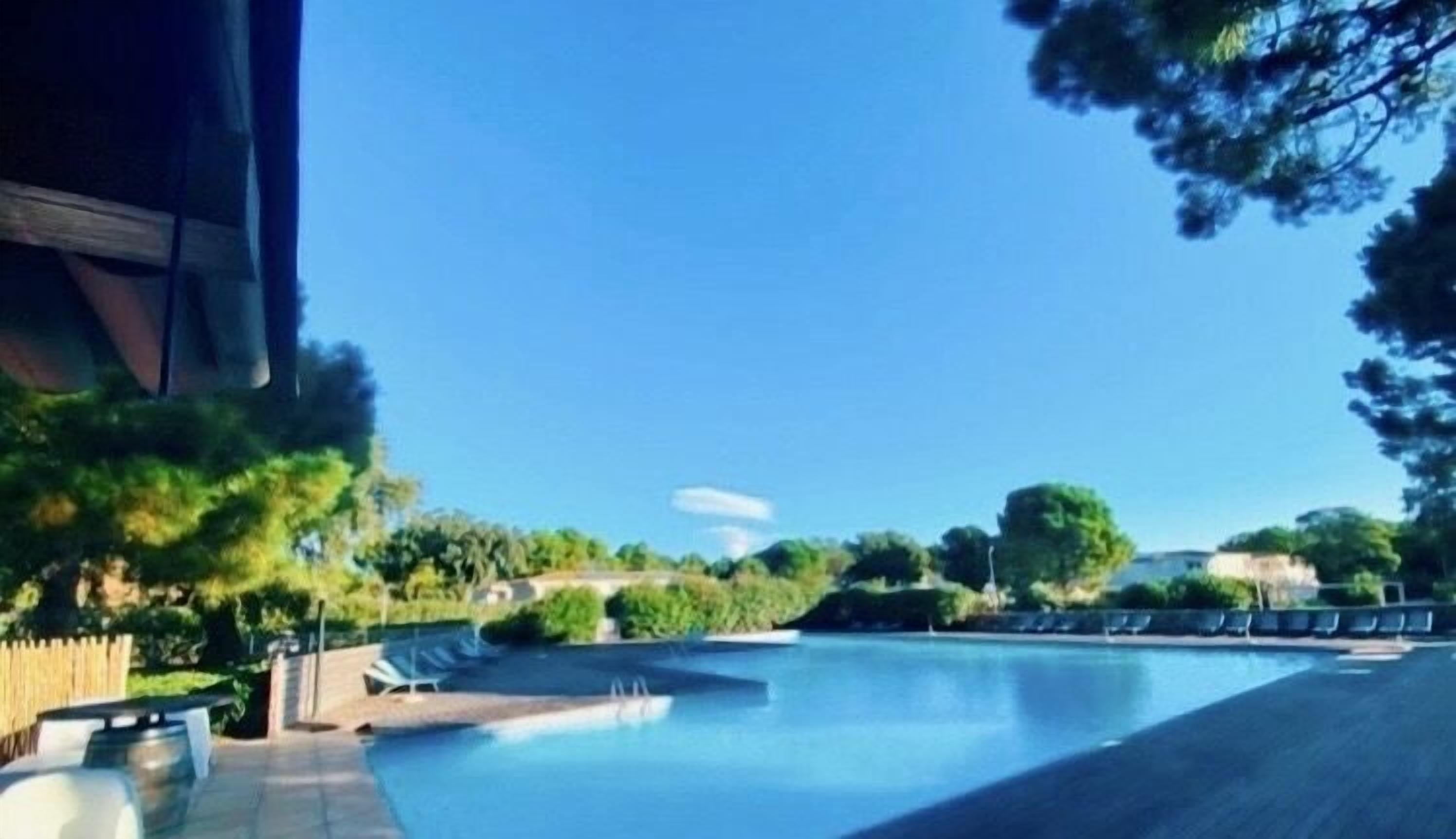 A swimming pool with lounge chairs and a clear blue sky.