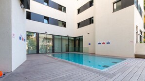 A modern indoor swimming pool with glass walls and a wooden deck. - Charming & Quiet 1 BR in Heart Tel Aviv SAFE ROOM (Tel Aviv-Yafo)