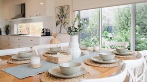 A dining area with a wooden table set for four, surrounded by white chairs.