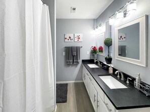 A modern bathroom with two sinks, a large mirror, and a shower curtain.