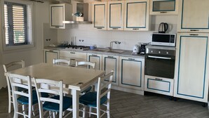 Una cocina con armarios blancos, cocina a gas, microondas y pileta.