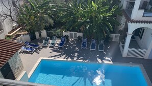 Una piscina con sillas de descanso y una cerca blanca.