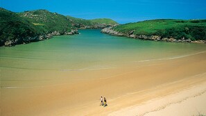 A beach with a clear view of the water and distant hills.