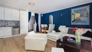 Una sala de estar moderna con un sofá blanco, una mesa de centro y un comedor con mesa y sillas.
