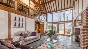 Amplia sala de estar con techo alto, chimenea y vistas al exterior.