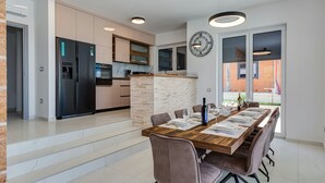 A modern kitchen with a built-in oven, a refrigerator, and a stone island. - Villa Kate ZadarVillas (Poljica-Brig)