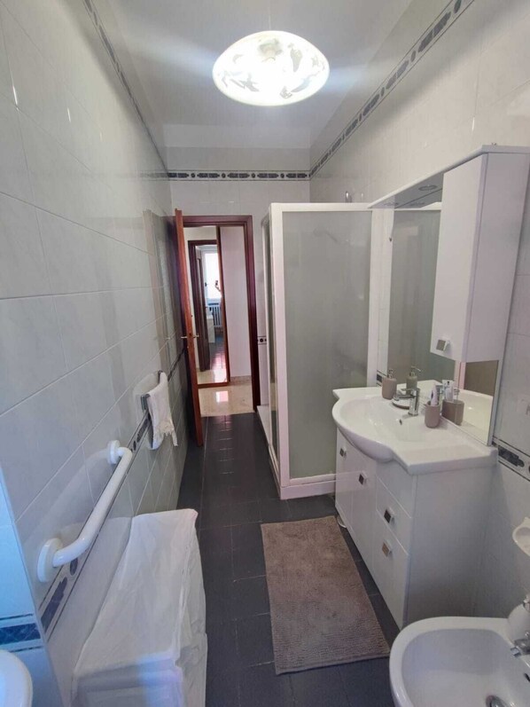 A modern bathroom with a walk-in shower, a large mirror, and a vanity with a sink.