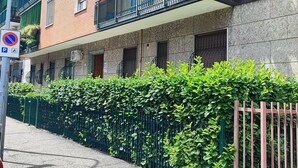 Un edifici residencial de diverses plantes amb balcons, un senyal de prohibició d'aparcament i una tanca de setí al llarg de la vorera.