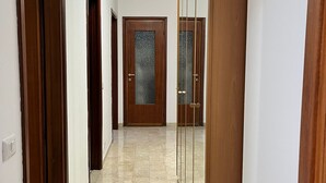 Passadís amb portes de fusta i una porta de vidre, que condueix a una habitació.