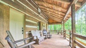 Une cabane en bois avec une véranda, des chaises en bois et un banc.