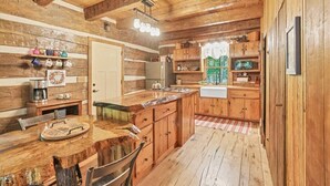 L’intérieur d’un chalet rustique en bois comprend un coin cuisine avec des placards en bois, une table à manger avec des chaises et un espace dédié au café.