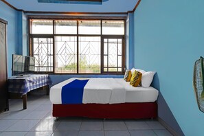 A bedroom with a bed, a TV, a table with a checkered tablecloth, and a window with metal bars. - Hotel O 139 Guest House (Bojongsoang)