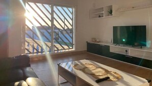 A modern living room with a large TV, a sofa, and a coffee table. - Chalet con Piscina Privada (Chiclana de la Frontera)