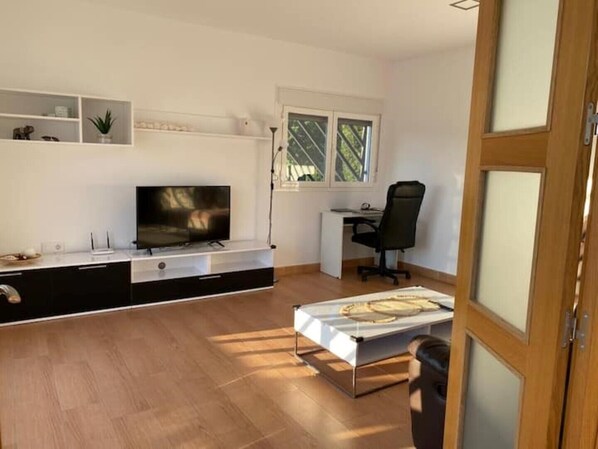 Un salon moderne avec un téléviseur à écran plat, un bureau et un fauteuil de bureau noir.