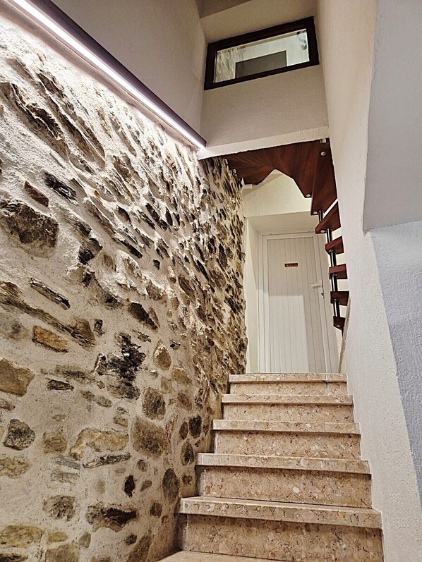 A stone wall with a wooden staircase leading to a white door. - Apartment + Terrace (6 rooms) with exceptional views and location, right on the water (Collioure)