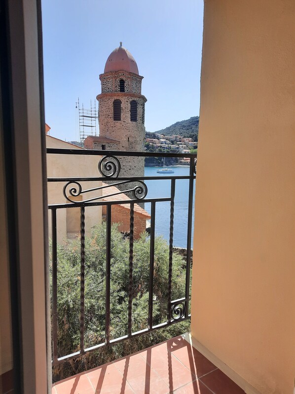 A balcony with a view of a historic tower and a body of water.