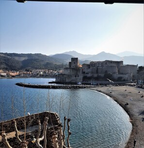 A coastal town with a historic fort, a sandy beach, and a calm sea.