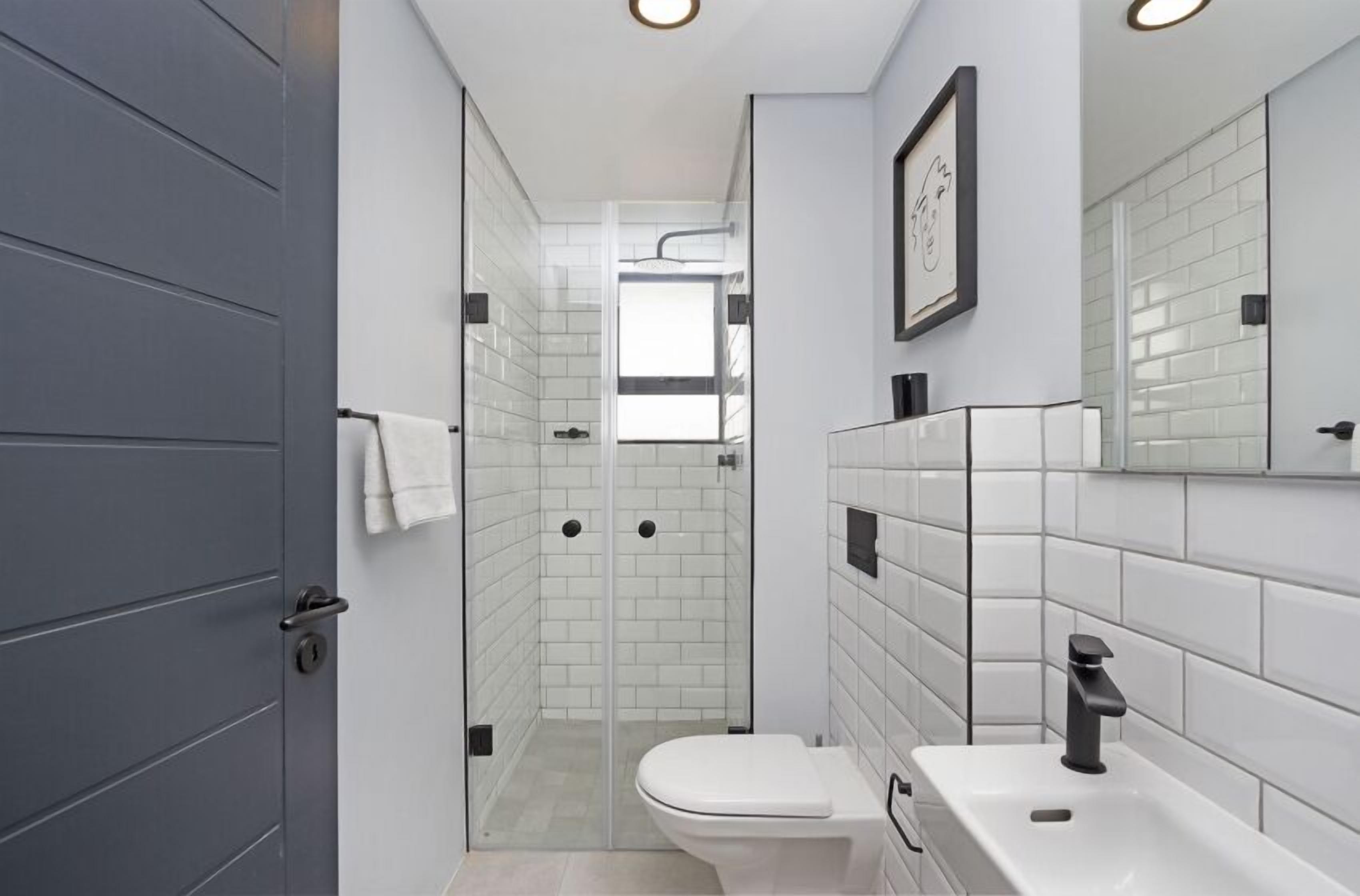 A modern bathroom with a glass-enclosed shower, a white toilet, and a sink with a black faucet.