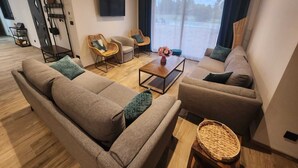 A modern living room with a sofa set, two armchairs, a coffee table, and a TV mounted on the wall. - Mas provençal climatisé avec piscine (Châteaurenard)