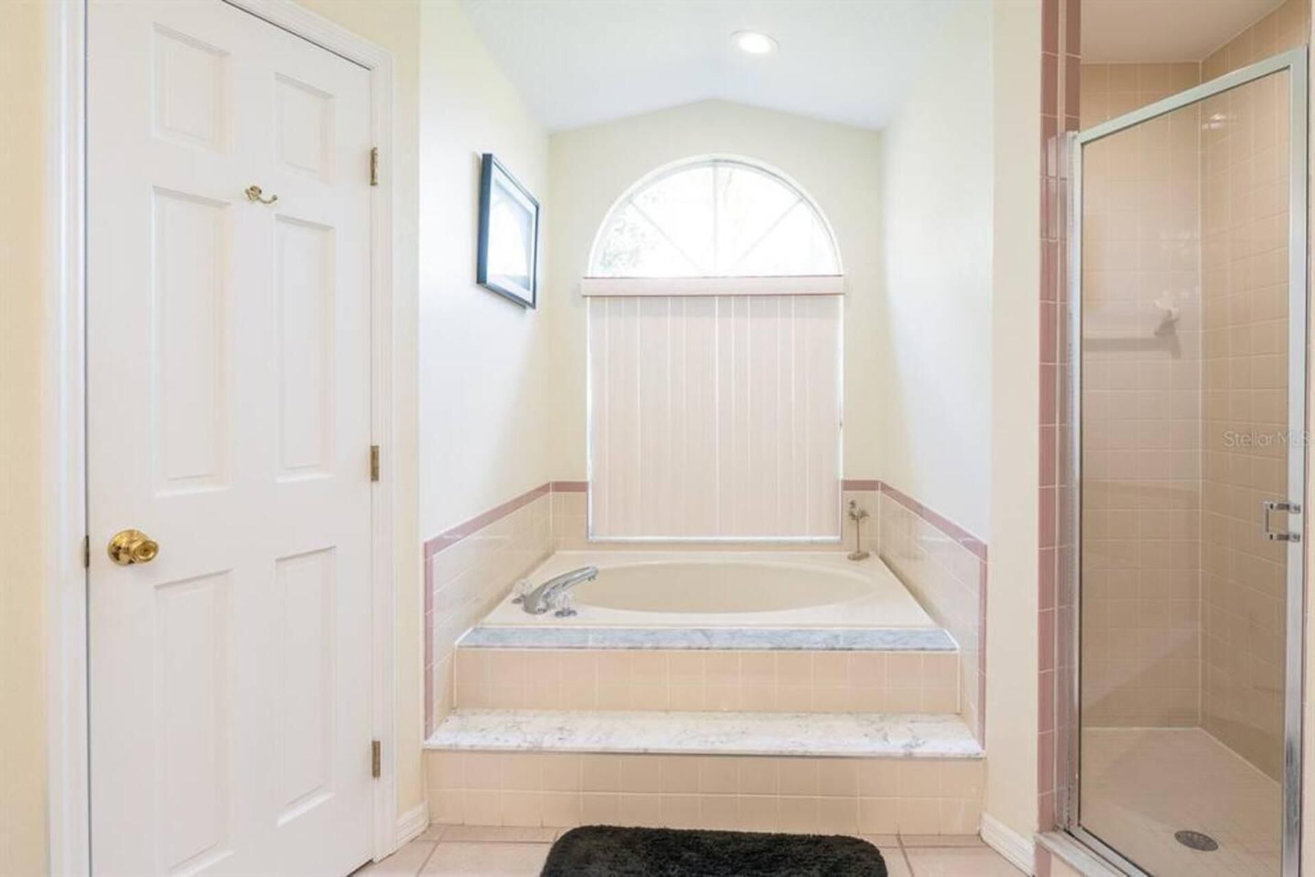 A bathroom with a bathtub, shower, and a door.