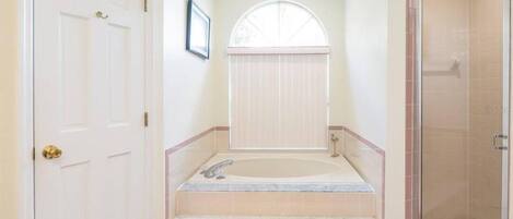 A bathroom with a bathtub, shower, and a door.