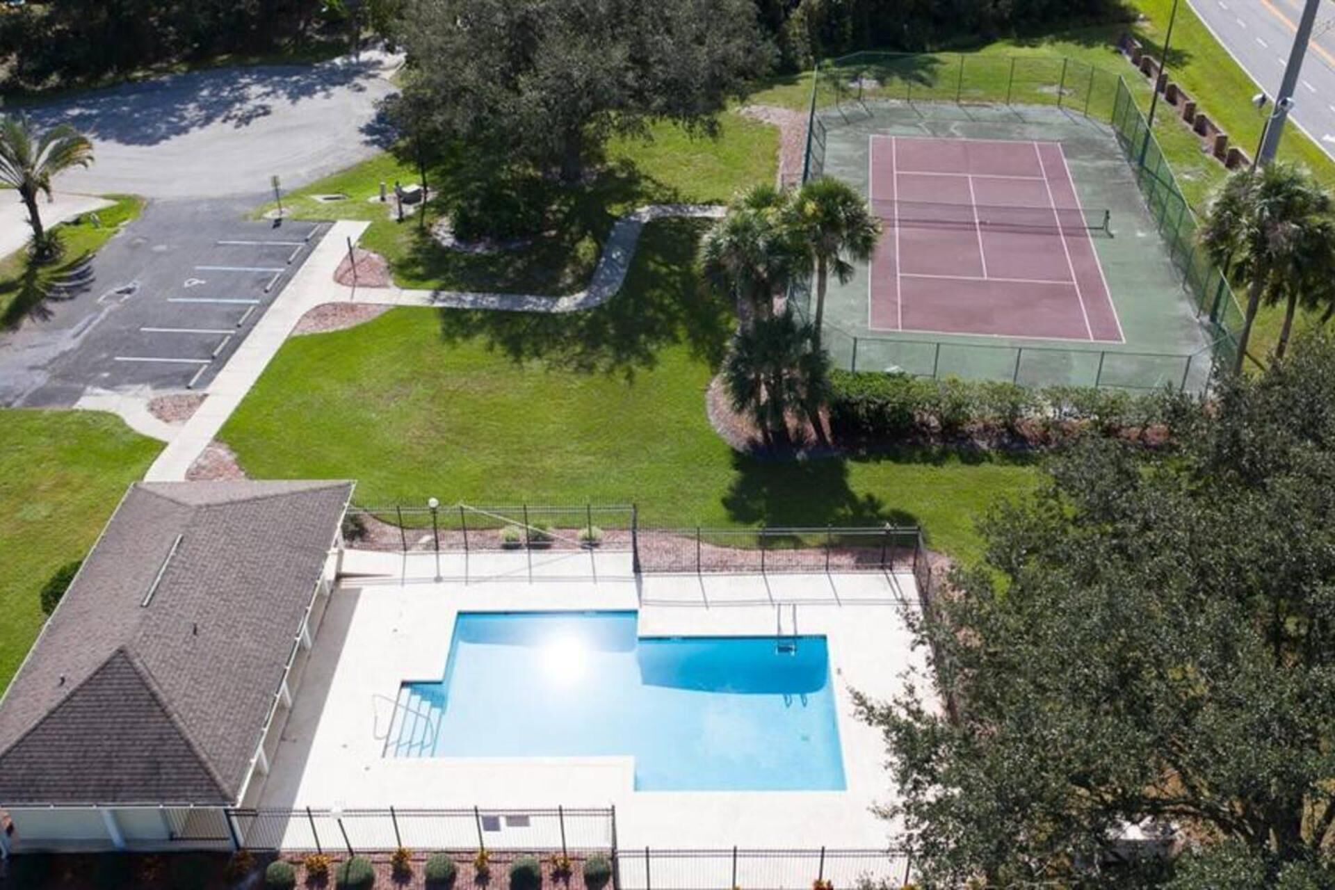 A residential area with a swimming pool, tennis court, and parking lot.