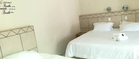 Habitación de hotel con dos camas, cabecera con diseño geométrico y pared decorada con citas motivacionales.