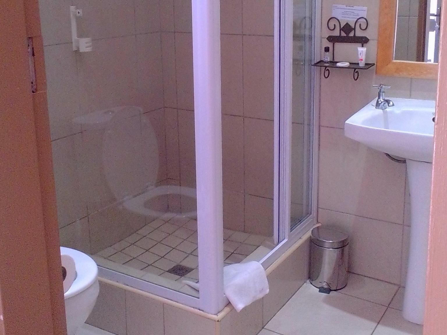Un baño con ducha de vidrio, inodoro y lavabo.