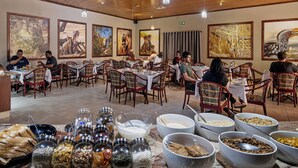 Un restaurante con varias mesas y sillas, grandes cuadros enmarcados de vida silvestre en las paredes y una variedad de alimentos exhibidos al frente.