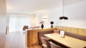A modern dining area with a wooden table and benches, a vase with flowers, and a pendant light. - Alpenstolz #1.01 Comfort (Damüls)
