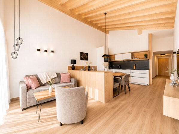 Ein zeitgemäßer Wohnraum mit einer Couch, einem Essbereich und einer Küche.