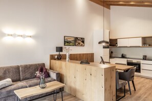 A modern living room with a sofa, a coffee table, and a wooden reception desk. - Alpenstolz #1.09 Exclusive (Damüls)