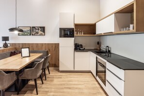 A modern kitchen with a dining area, wooden cabinets, a microwave, and a coffee machine. - Alpenstolz #1.09 Exclusive (Damüls)