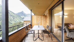A balcony with a table and chairs, a wooden floor, and a mountain view. - Alpenstolz #2.01 Comfort (Damüls)
