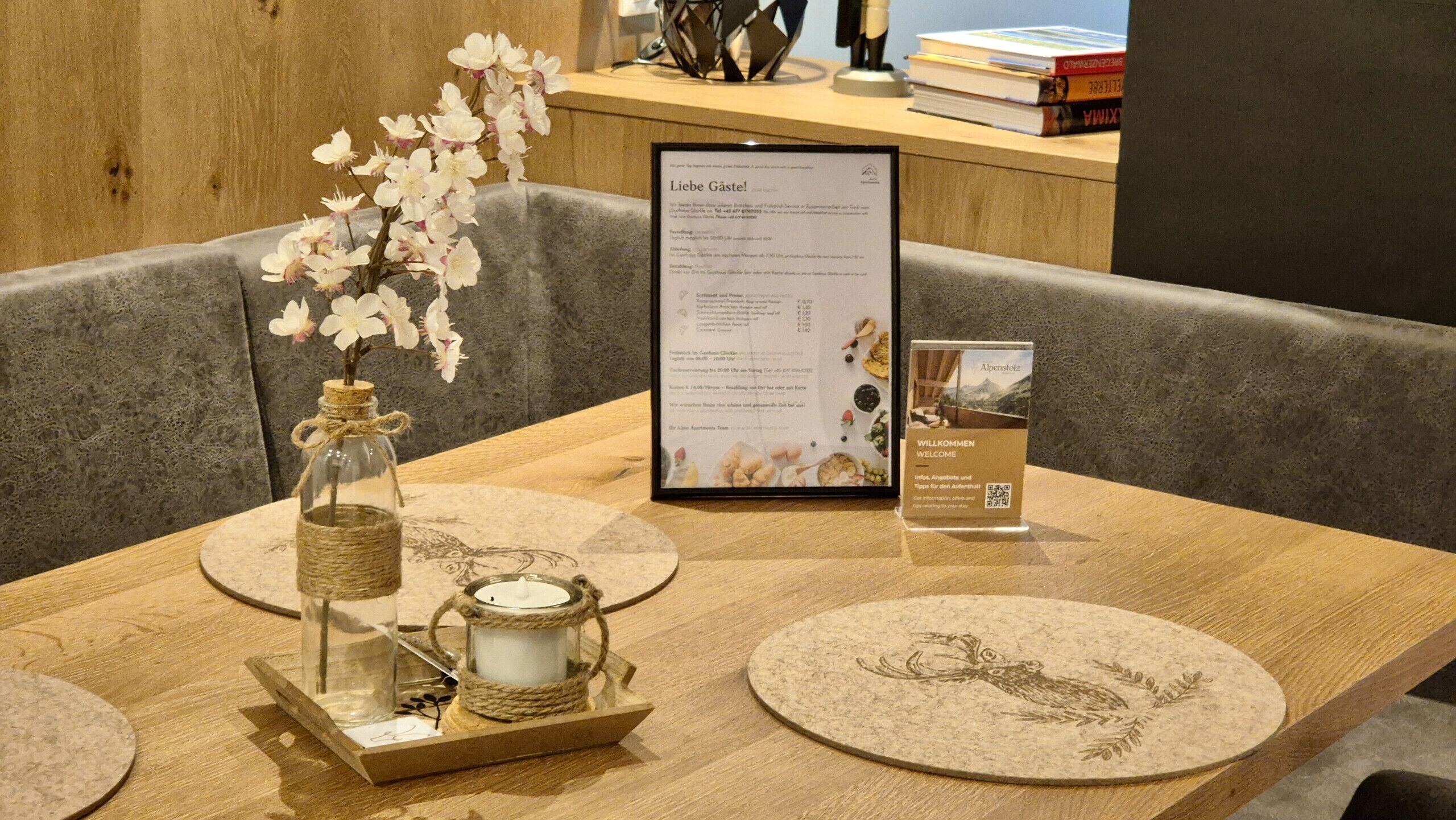A wooden table with a menu, a candle, and a decorative glass jar with flowers.