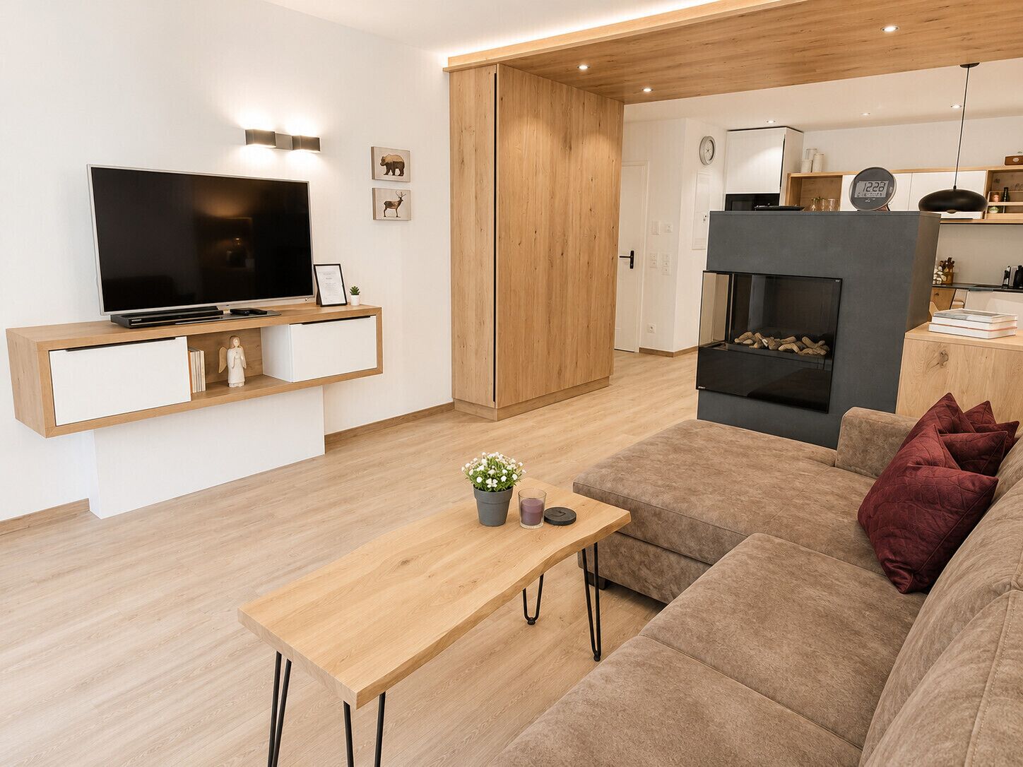 A modern living room with a flat-screen TV, wooden furniture, a fireplace, and a cozy sofa.